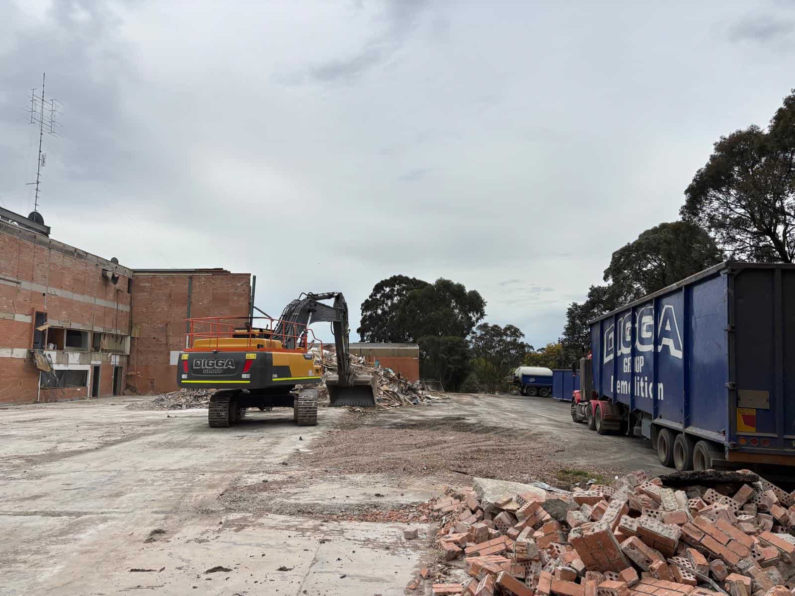 Digga Group excavator demolishing a studio building beside a Digga Group haulage truck at the former WIN Television site, Walker St Ballarat North